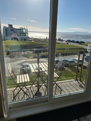 a window with a view of the beach and the ocean at Beach View Flat on Coastal Path in Llanelli