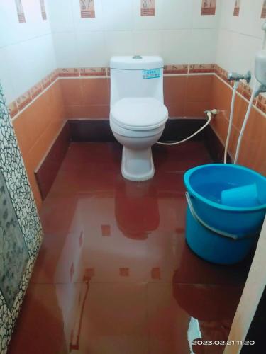 een badkamer met een toilet en een blauwe emmer bij Le Grace Eden in Madurai