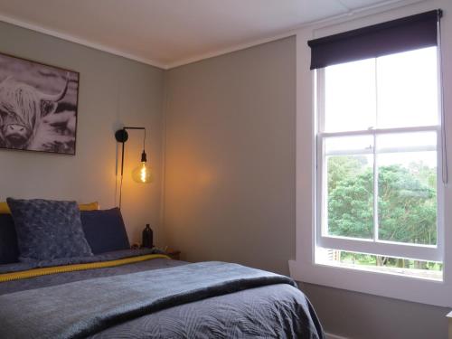 a bedroom with a bed and a window at Crown Ridge Miners Cottage in Karangahake