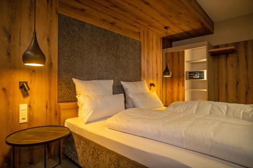 a bedroom with a white bed with a table at GUESTHOUSE FELSENLAND in Dahn