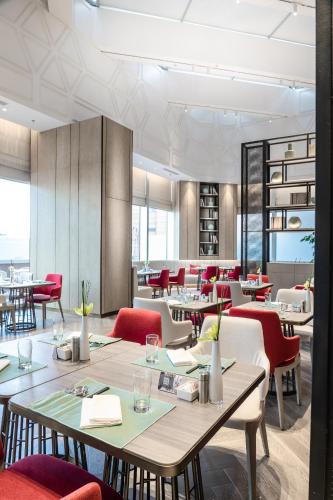 a dining room with tables and red chairs at Conrad Shanghai in Shanghai