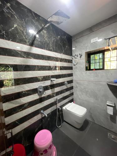 a bathroom with a white toilet and a wooden wall at Hash Homestay in Kārwār