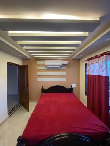 a room with a large bed with a red blanket at Hash Homestay in Kārwār
