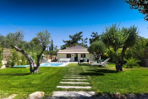 a garden with a house and a swimming pool at CRETAN VILLA OLIVIA in Karteros