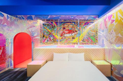 a bedroom with a colorful mural on the wall at BnA WALL in Tokyo