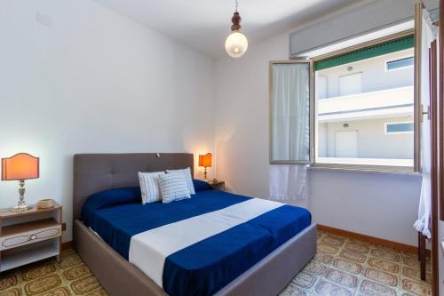 een slaapkamer met een blauw en wit bed en een raam bij Appartamento Vespucci Bilo - MyHo Casa in Tortoreto Lido