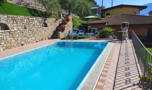 una piscina in un cortile con un muro di pietra di Casa Elka Residence Lake view and pool by Garda Domus Mea a Pieve