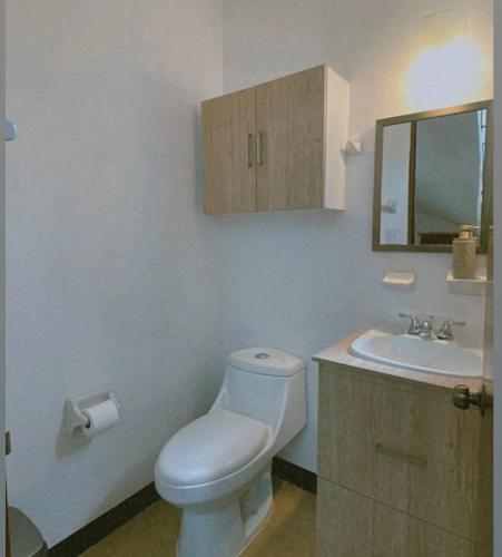 a bathroom with a toilet and a sink and a mirror at Casa Amapolas Oaxaca in Oaxaca City