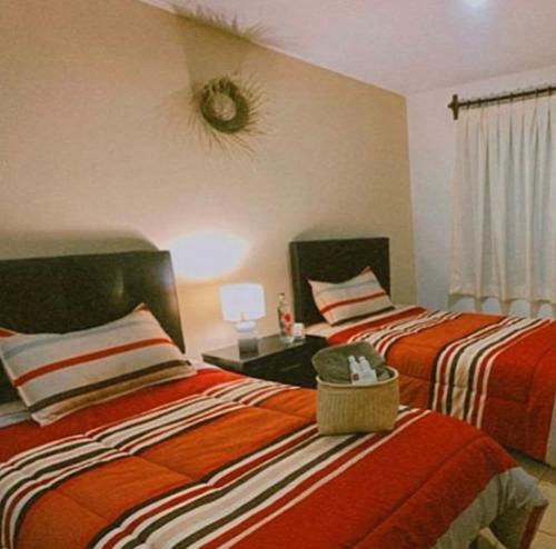 una camera con 2 letti con lenzuola bianche e arancioni di Casa Amapolas Oaxaca a Città di Oaxaca