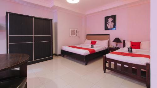 a hotel room with two beds and a table at RedDoorz Plus at Holiday Plaza Hotel Tuguegarao City in Tuguegarao City
