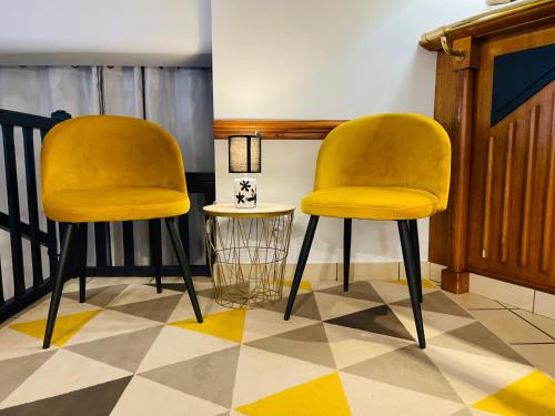 two yellow chairs sitting on a checkered floor at Restaurant Hotel Logis Chez Sophie in Briouze