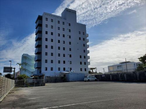 a large white building with a car parked in a parking lot at Miyako Daiichi Hotel in Miyako Island