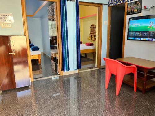 a dining room with a table and a red chair at VAIBHAV HOME STAY in Hampi