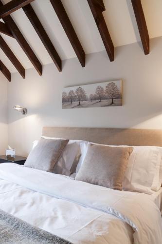 a bedroom with a bed with white sheets at Hurtwood Hotel in Peaslake