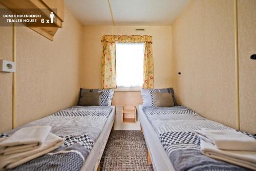 two beds in a small room with a window at MOLO RESORT KEMPING in Osiek