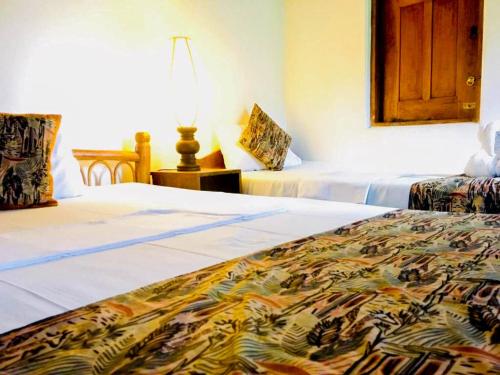 a hotel room with two beds and a lamp at Eth Mansala in Sigiriya