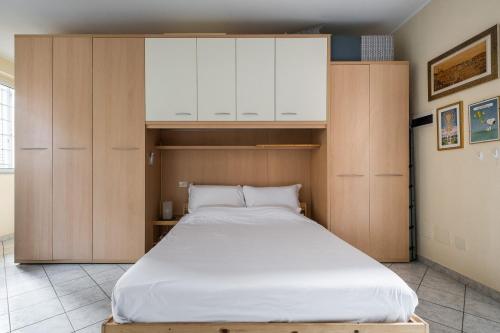 Cette chambre comprend un grand lit et des placards en bois. dans l'établissement Studio Calari with terrace by Wonderful Italy, à Bologne