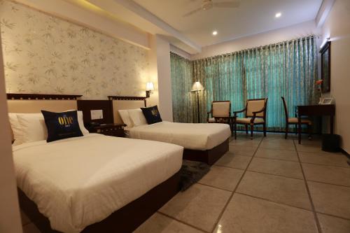 a hotel room with two beds and a table and chairs at The One Hotel in Aurangabad