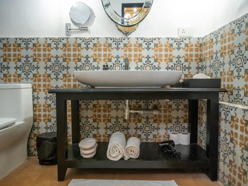 a bathroom with a sink and a shelf with towels at Fort Tiracol Goa in Arambol