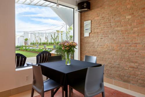 una mesa negra con sillas y un jarrón de flores. en California Hotel en Dalat