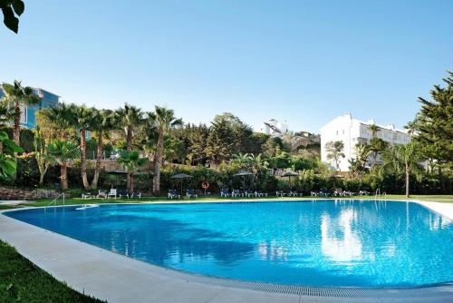 una gran piscina azul con sillas y árboles en Apartamento Costa Zahara en Zahara de los Atunes