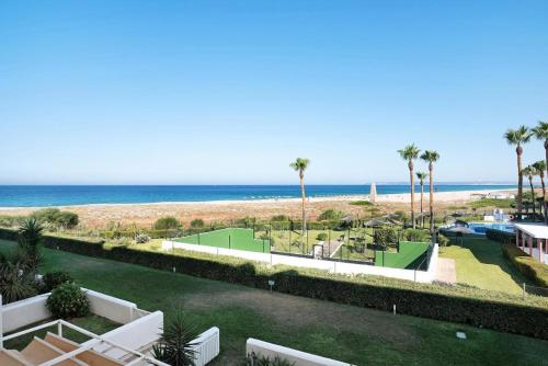 a view of a beach with palm trees and the ocean at Apartamento Costa Zahara in Zahara de los Atunes