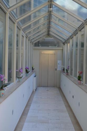 an empty hallway of a conservatory with plants and a door at Casa per ferie religiosa Figlie di Nazareth in Pisa