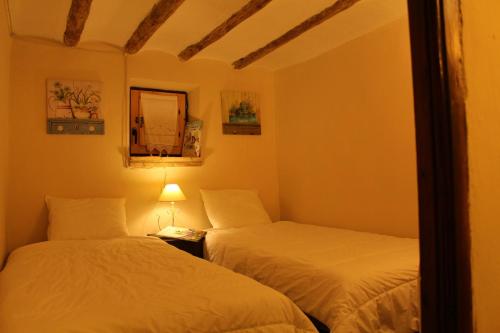 ビジャフランカ・デル・シドにあるCasa Rural Las Dalias con Hidromasajeのベッドルーム1室(ベッド2台、ランプ、鏡付)