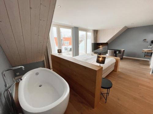 a bathroom with a sink and a bed and a tub at Hello Zeeland - Studio's Zuidstraat 1 in Domburg