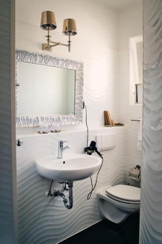 a white bathroom with a sink and a toilet at Boutique Hotel Villa Sarah in Düsseldorf