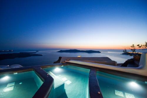 a swimming pool with a view of the ocean at night at Sophia Luxury Suites in Imerovigli