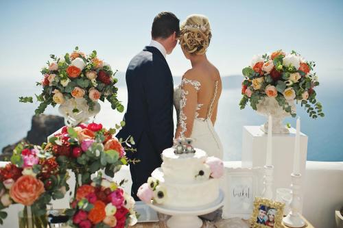 a bride and groom standing next to a wedding cake at Sophia Luxury Suites in Imerovigli