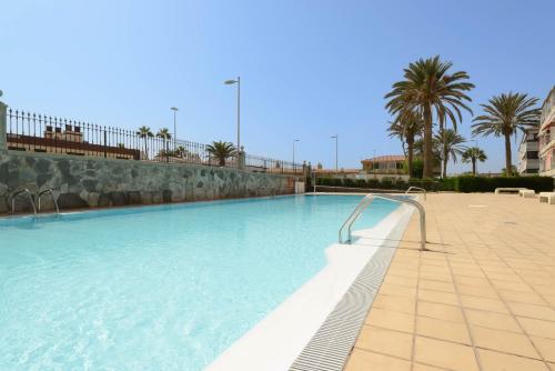 duży basen w ośrodku z palmami w obiekcie Ático Apartamento Las Burras Playa w mieście San Agustin