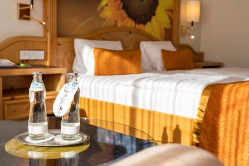 two bottles on a glass table next to a bed at CESTA GRAND Aktivhotel & Spa in Bad Gastein