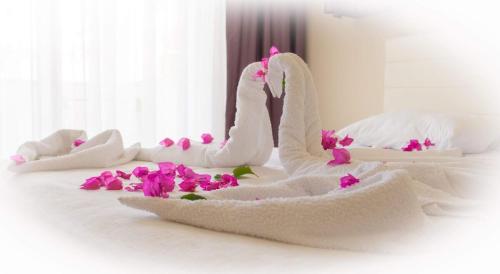 a white towel swan sitting on a bed with flowers at Agva Apart Otel in Kemer