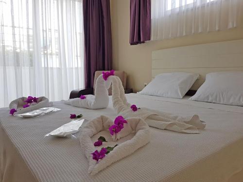 ein Bett mit Handtüchern und lila Blumen darauf in der Unterkunft Agva Apart Otel in Kemer