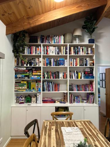 a book shelf filled with books in a room with a table at Two Mountains Lodge - Modern Alpine Retreat with Spa - 3mins to Mt Buller in Mount Buller