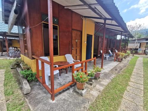 a house with a table and a bench outside at Cheers Garden Chalet in Kampung Tekek