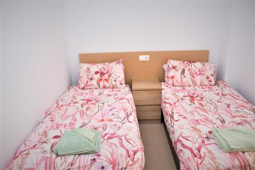 1 dormitorio con 2 camas con sábanas rosas y almohadas verdes en Gwen El Rincon, en Playa Flamenca