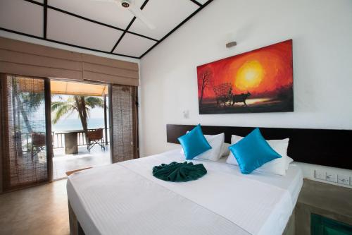 a bedroom with a large white bed with blue pillows at Hikks Villa in Hikkaduwa