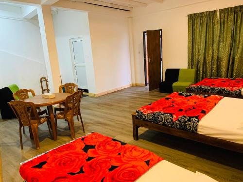 a room with two beds and a table with red roses at Sinora Holiday Bungalow in Nuwara Eliya