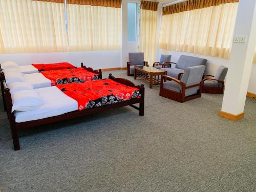 a bedroom with a bed with a red blanket and chairs at Sinora Holiday Bungalow in Nuwara Eliya