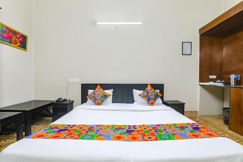 a bedroom with a large white bed with colorful pillows at FabHotel Harmony in Colonelganj