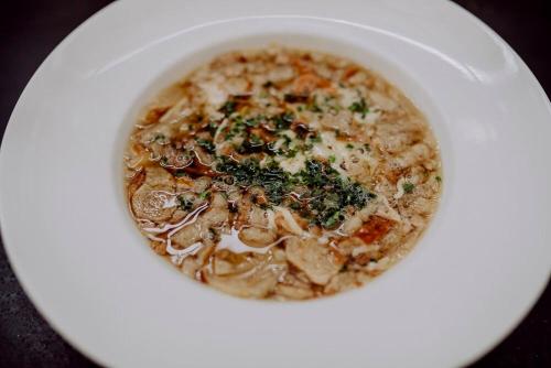 a white bowl of soup on a white plate at Hirzinger - Gasthaus und Hotel in Riedering