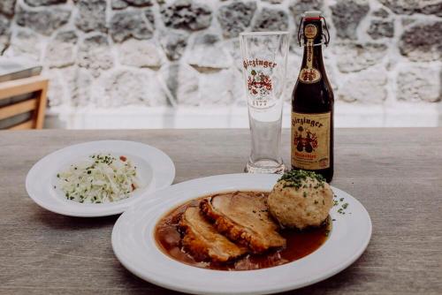 a table with a plate of food and a bottle of beer at Hirzinger - Gasthaus und Hotel in Riedering