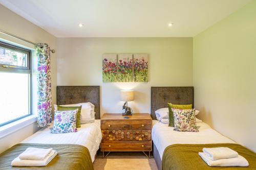 two twin beds in a room with a window at Birch Lodge 12 with Hot Tub in Newton Stewart