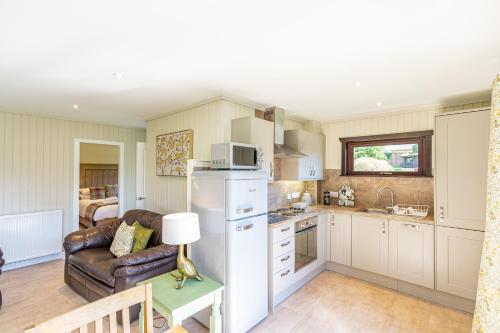 a kitchen with a white refrigerator and a couch at Birch Lodge 12 with Hot Tub in Newton Stewart