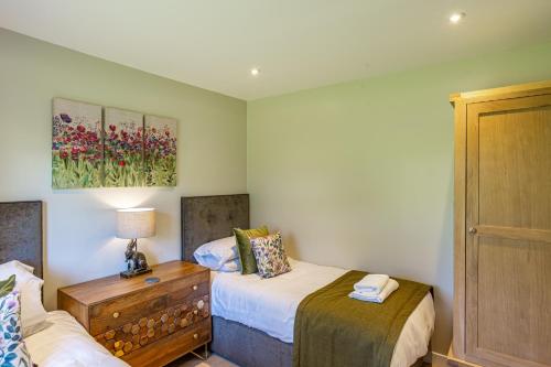 a small bedroom with two beds and a dresser at Birch Lodge 12 with Hot Tub in Newton Stewart