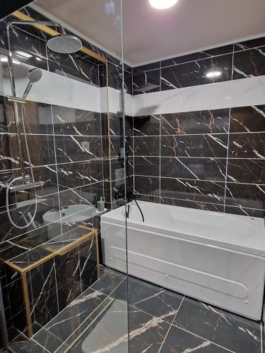 baño con paredes de azulejos negros y lavabo blanco en Fantastico Exlcusive Hotel en Senta