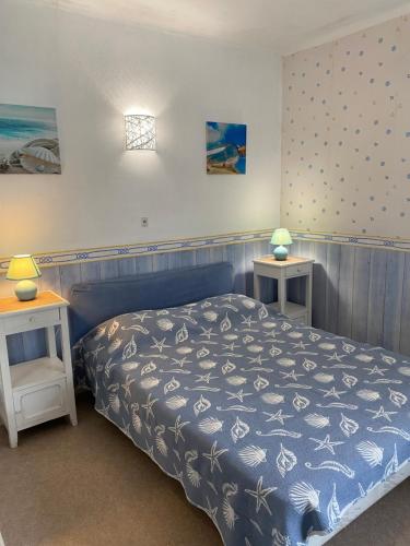 a bedroom with a blue bed and two tables at Les Tilleuls in Le Pouliguen